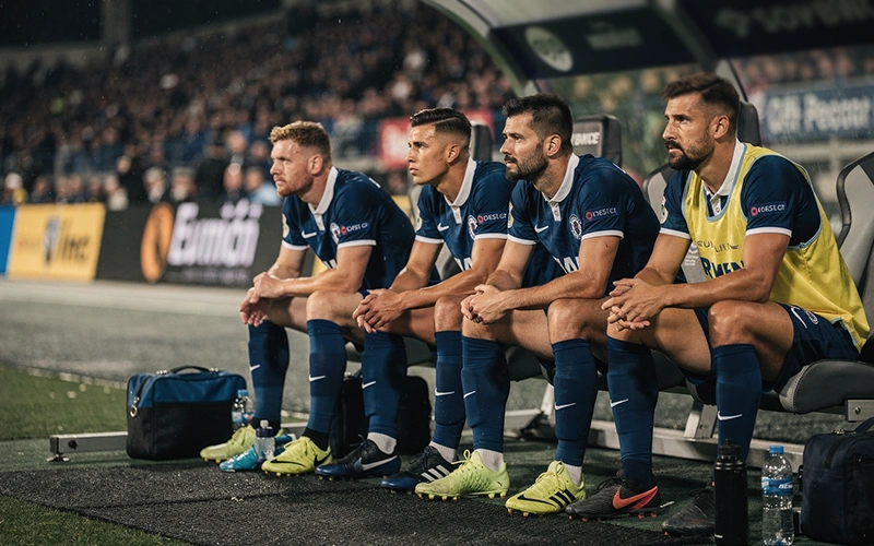 Fußballspieler sitzen konzentriert auf der Ersatzbank während eines Spiels